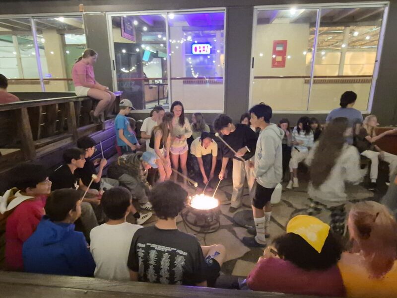 7th graders gather around a campfire to make s'mores