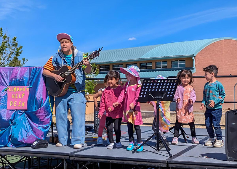 Children sing and dance onstage with Jules, known for appearances on the Ms. Rachel Show.