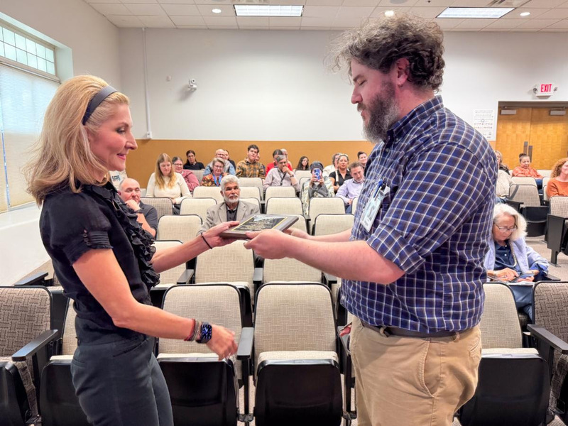 Vanessa Romero, Deputy Superintendent of Teaching and Learning, hands Brian Smith, a teacher at Santa Fe High School his award.
