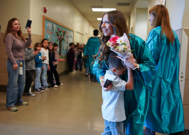Isaac Galaviz Campos, a kindergartener at El Camino Real Academy, embraces his sister, Alexa Galaviz, after presenting her with a bouquet of flowers during Capital High School’s Graduate Parade.