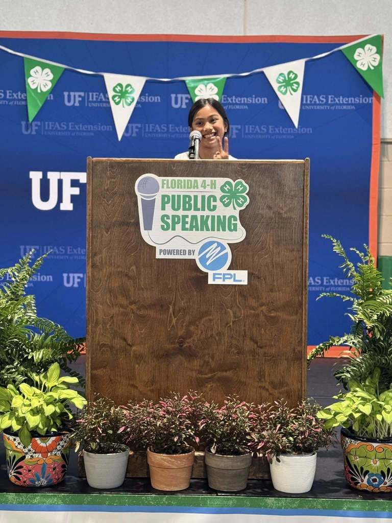 Mikaela Mejia smiling and posing from behind a speaker's podium