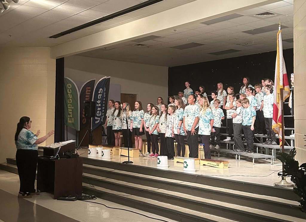 The Navigator choir standing on stage while being conducted by Ms. Richbourg.