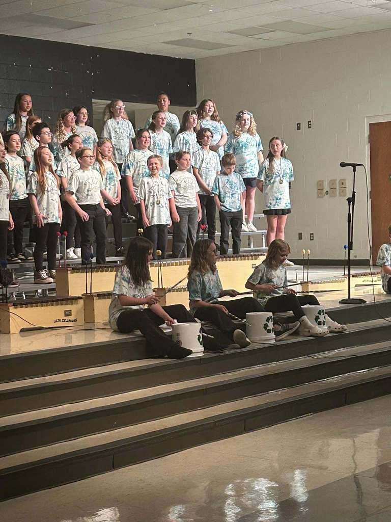 The Navigator choir standing on stage while bucket drummer play on the steps.