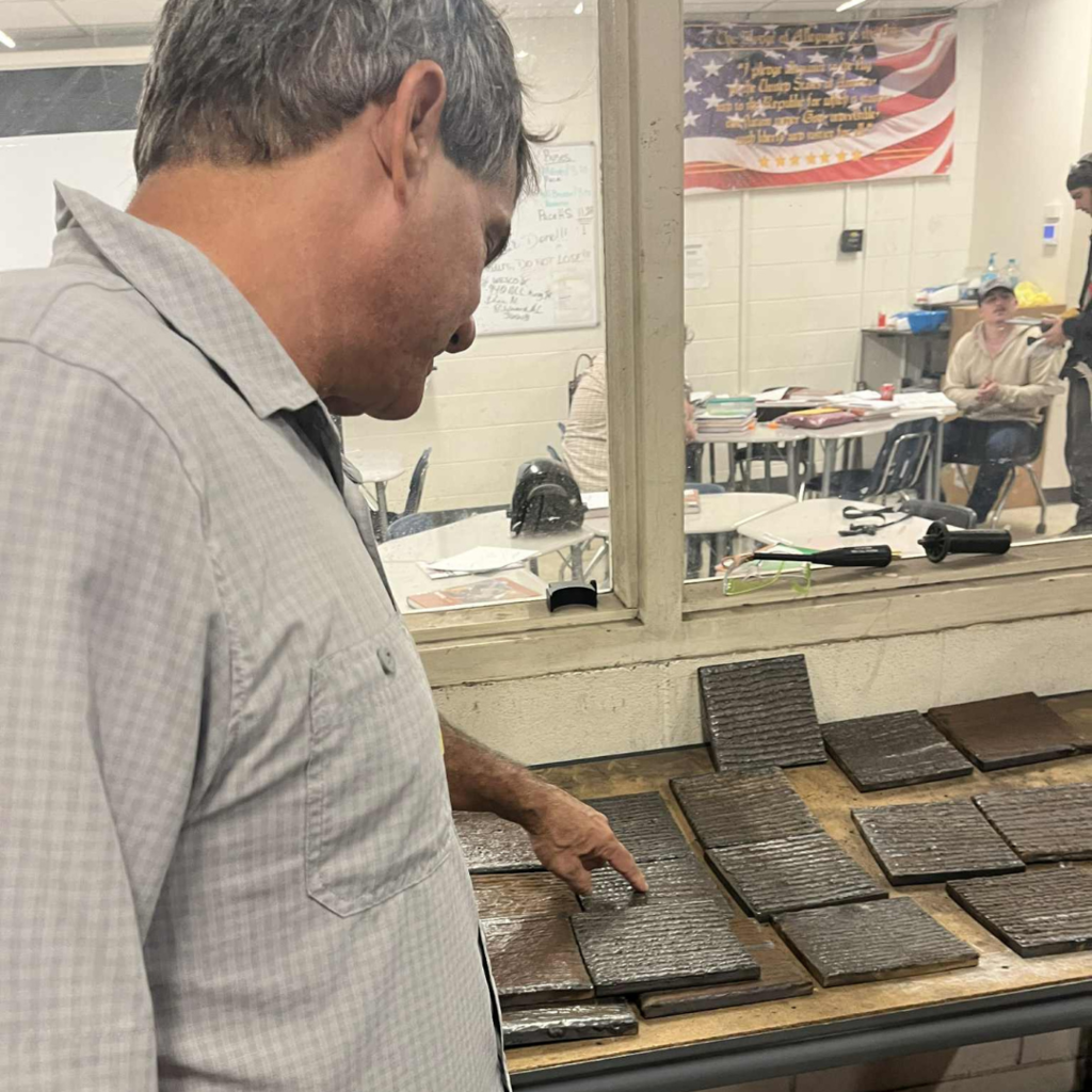 Looking over student welding plates.