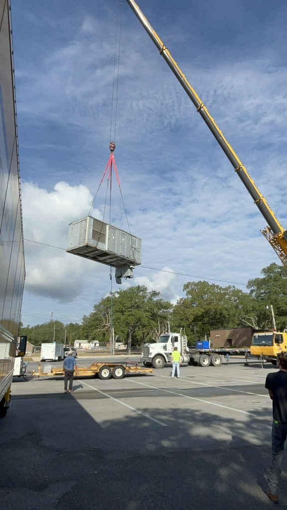 Crane removing HVAC system and positioning it on a trailer