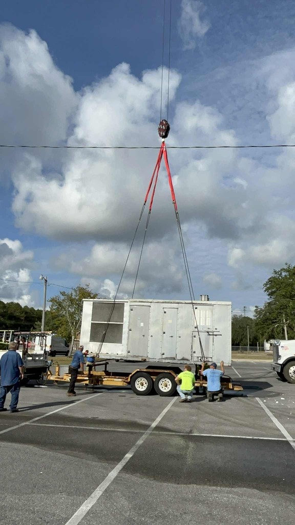 Crane placing old HVAC system on trailer