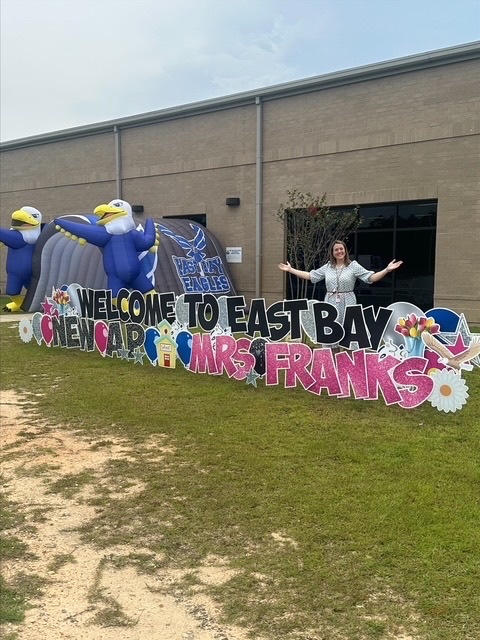 Mrs. Emily Franks celebrates her first day as East Bay K-8 Assistant Principal beside a colorful welcome display and East Bay Eagle decorations.