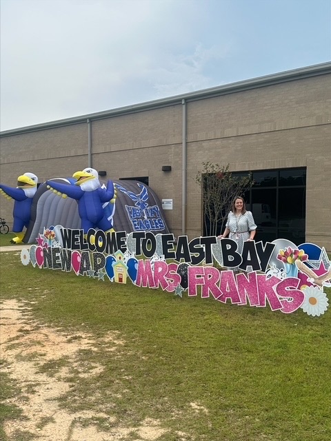 Mrs. Emily Franks celebrates her first day as East Bay K-8 Assistant Principal beside a colorful welcome display and East Bay Eagle decorations.