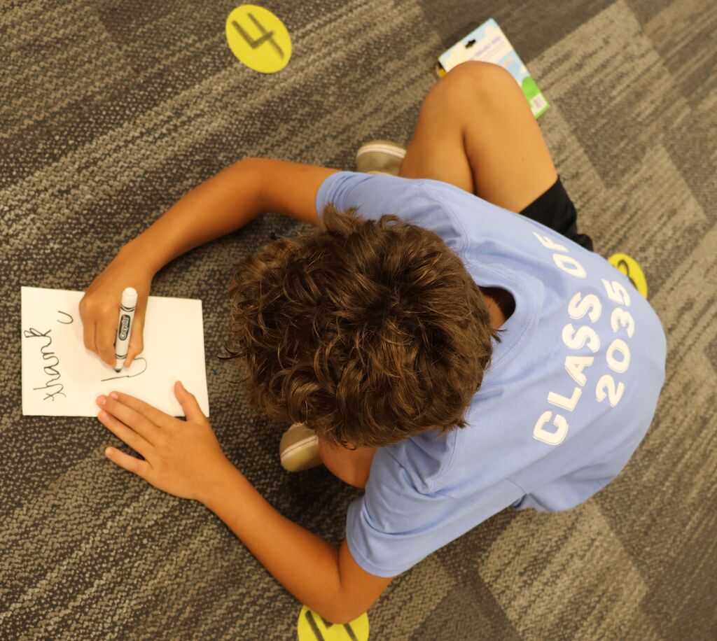 Student writing a thank you note to guest speakers