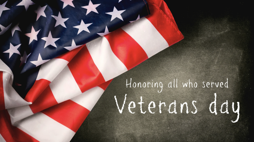 Chalkboard background with a folded American Flag. Text reads: Honoring all who served. Veteran's Day.