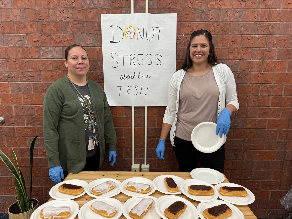 Our principals standing by the donut table with a sign that says "DONUT stress about the test!"