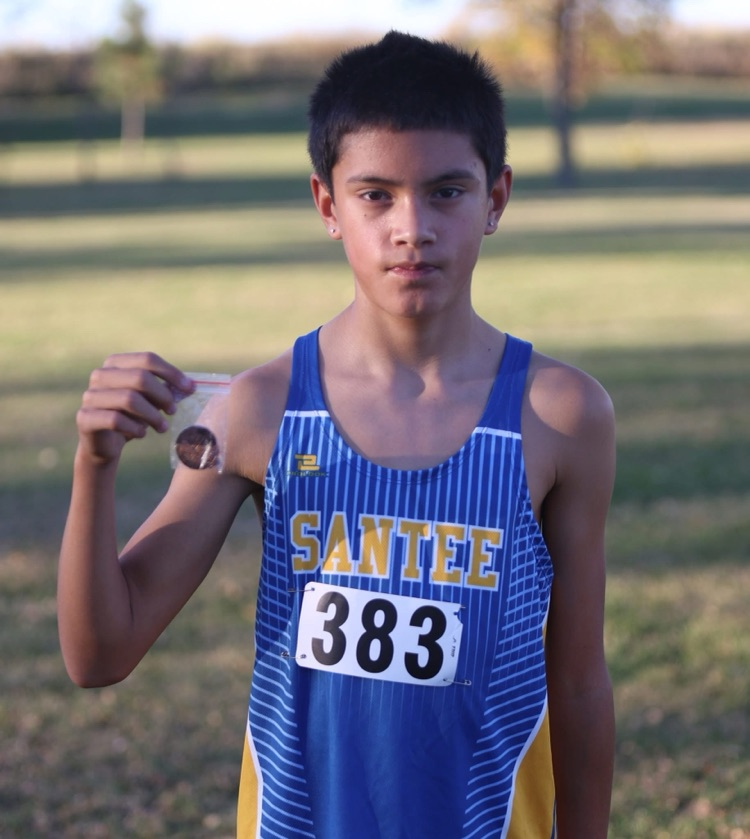 picture of a student in a blue jersey holding up his medal