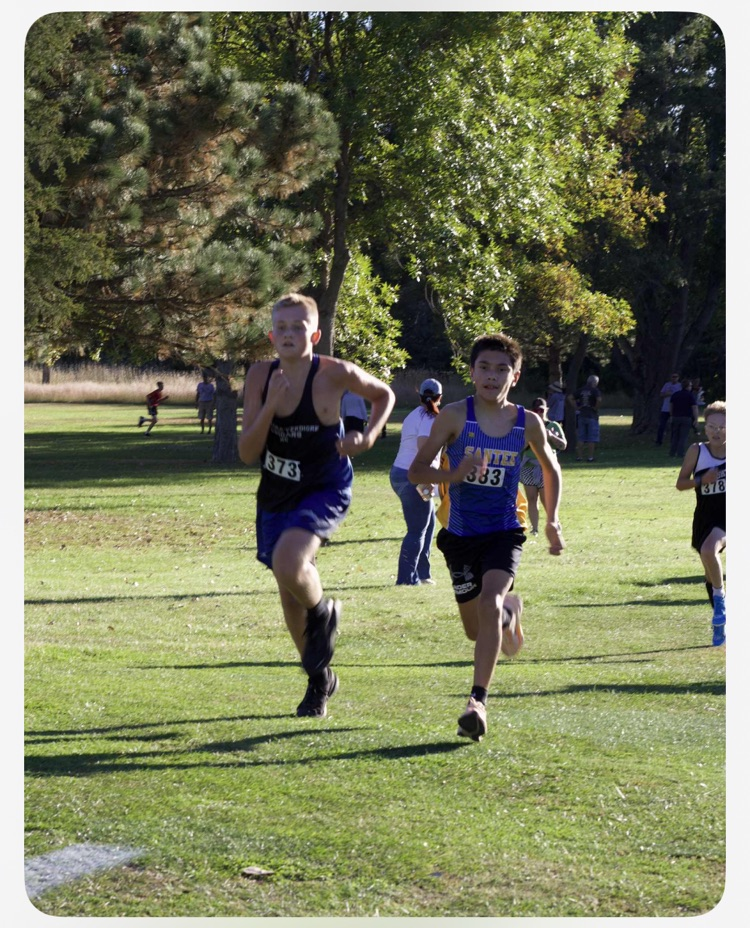 picture of our cross country athlete running on grass with his blue jersey on