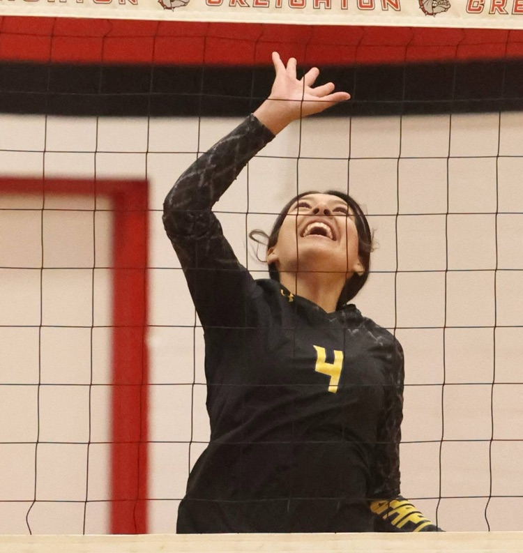 student volleyball player in her black jersey hitting the ball over the net