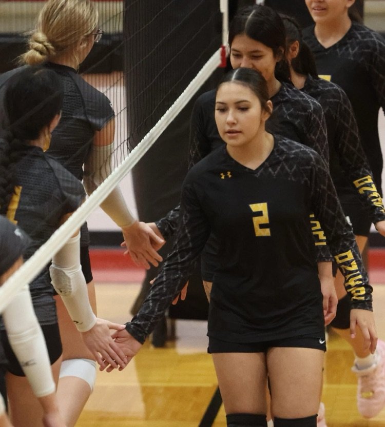 student volleyball players in their black jerseys congratulating their opponents right up to the volleyball net