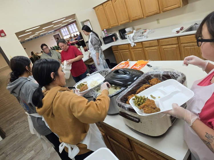 students preparing plates of food for elders 