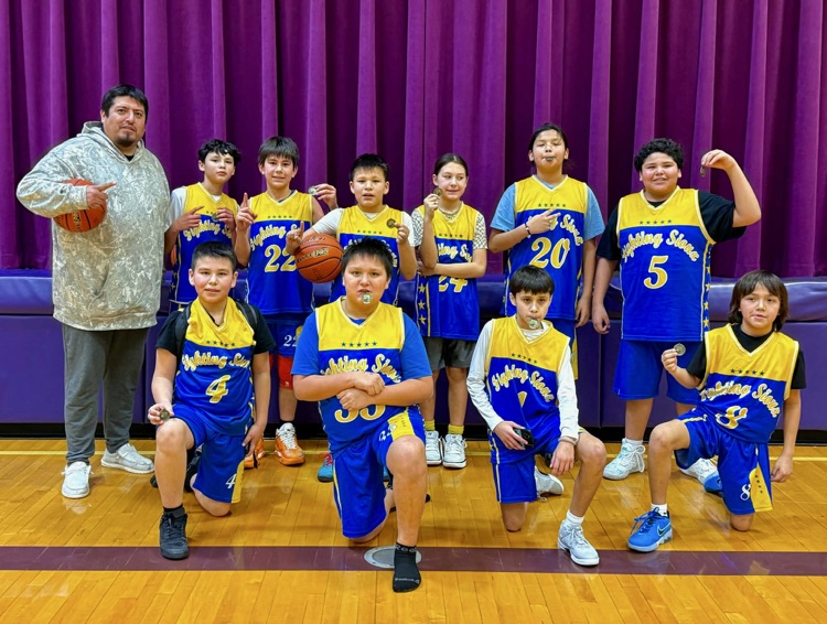 team photo of 5/6 grade boys in blue and yellow basketball jerseys holding their championship medals