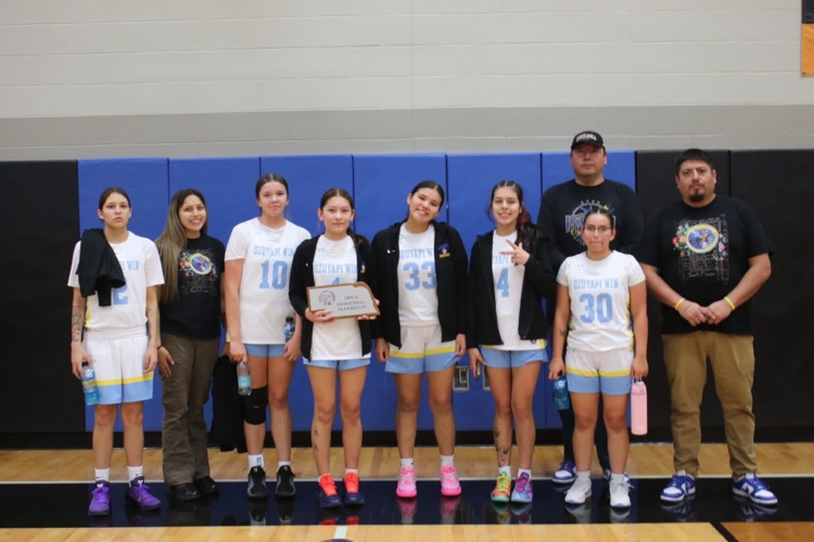 girls basketball team picture. conference tournament runner up. team in white jerseys with a blue and gray background.