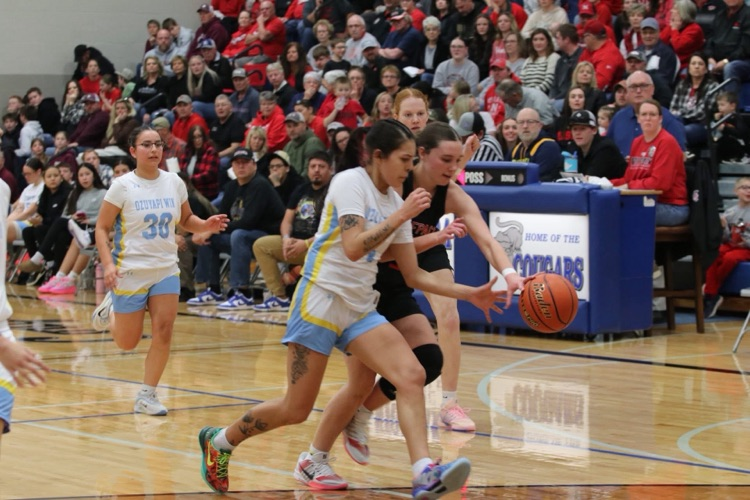 Isanti girls basketball player with a white jersey dribbling down the court at a basketball game against a player in a black jersey