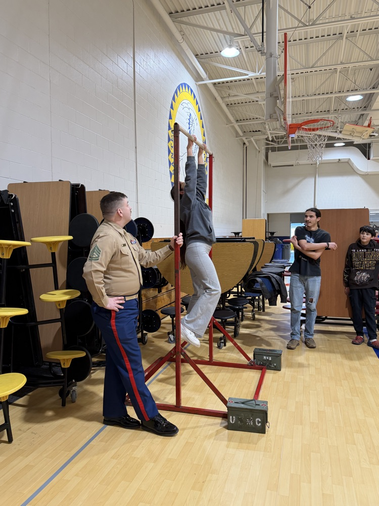 Photo of a female student doing pull ups on some red bars.