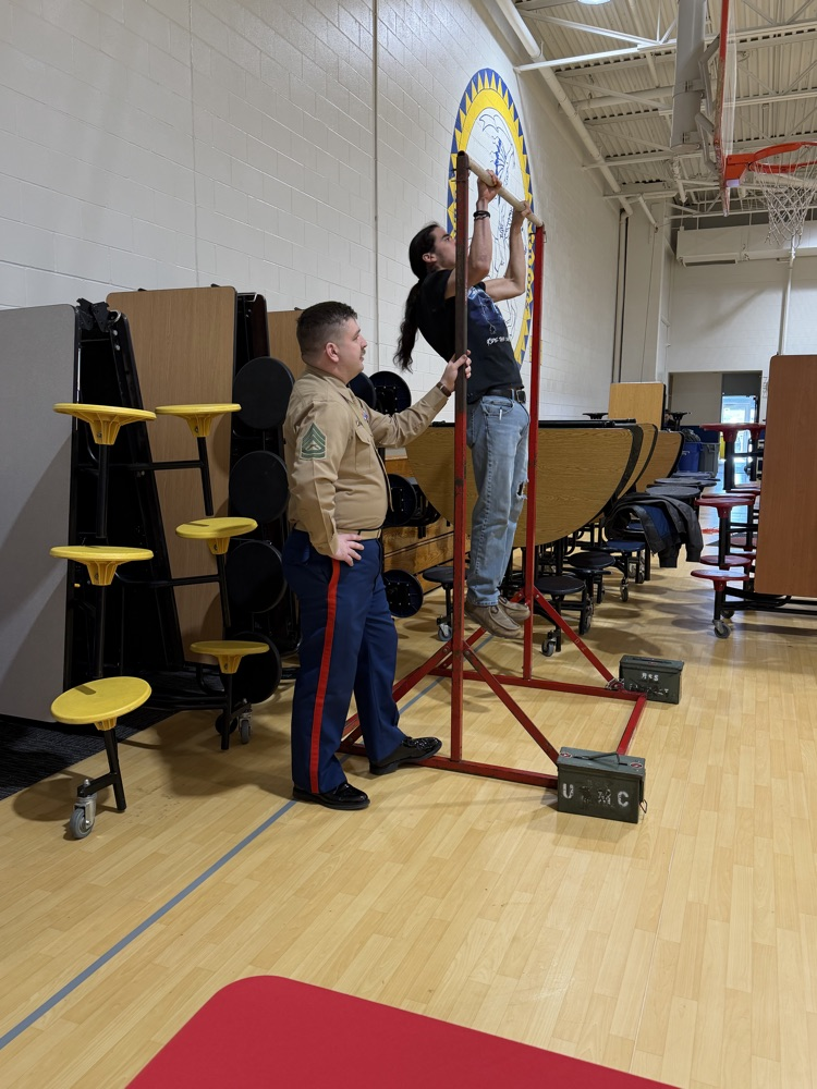 Photo of a male student doing pull ups on some red b