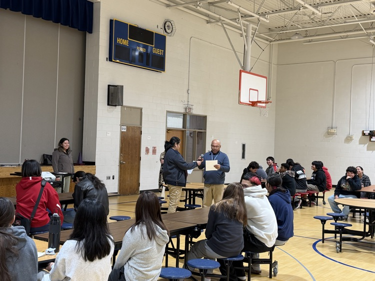 Photo of staff doing a skit and students sitting at tables.