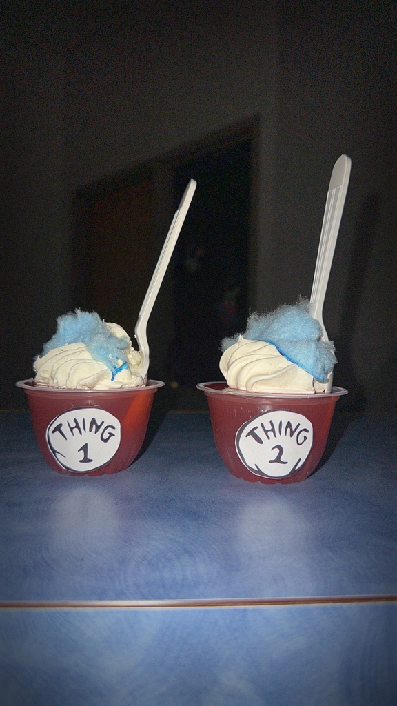 cups of red jello with white whipped cream and blue cotton candy treat