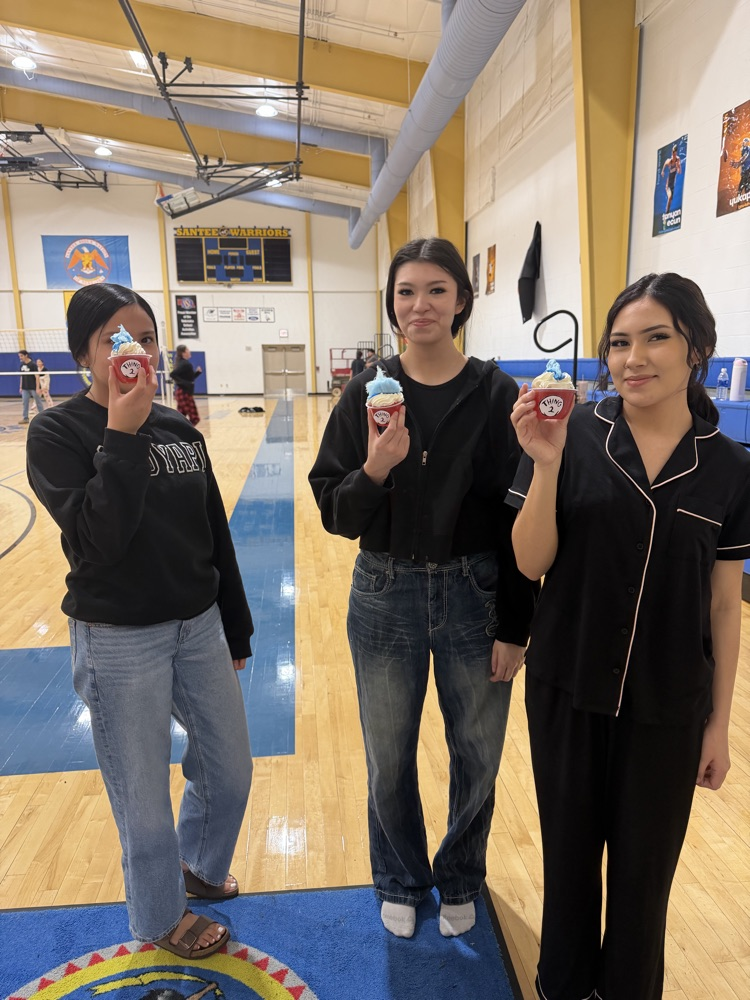 3 female students holding their red cups of jello with the basketball court in the background