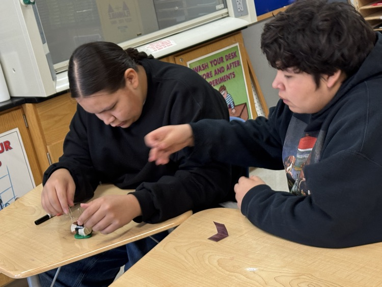 students using materials to build a simple electric motor with batteries, wires etc
