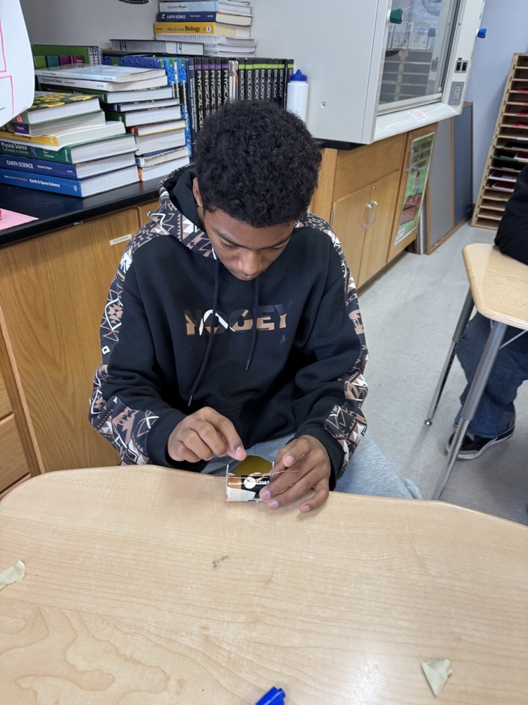 students using materials to build a simple electric motor with batteries, wires etc