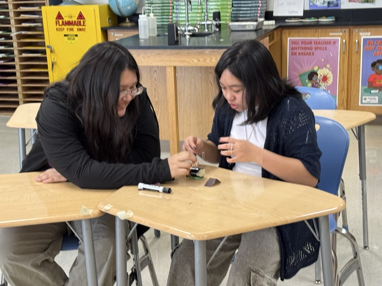 students using materials to build a simple electric motor with batteries, wires etc