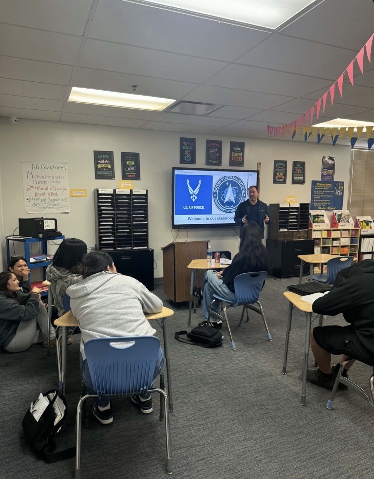 a classroom full of students listening to a gentlemen from the military speak