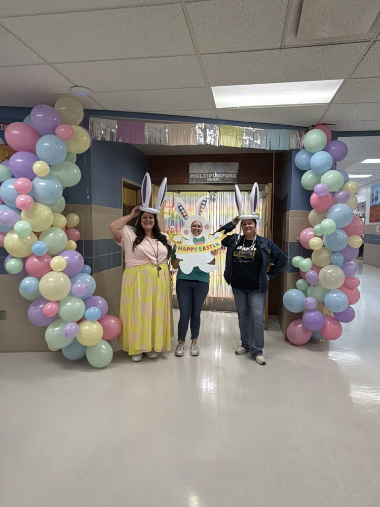 3 females standing by a pastel ballon arch with bunny ears on