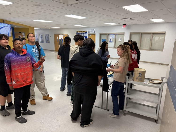 students standing in line at a folding table to put toppings in their ice cream