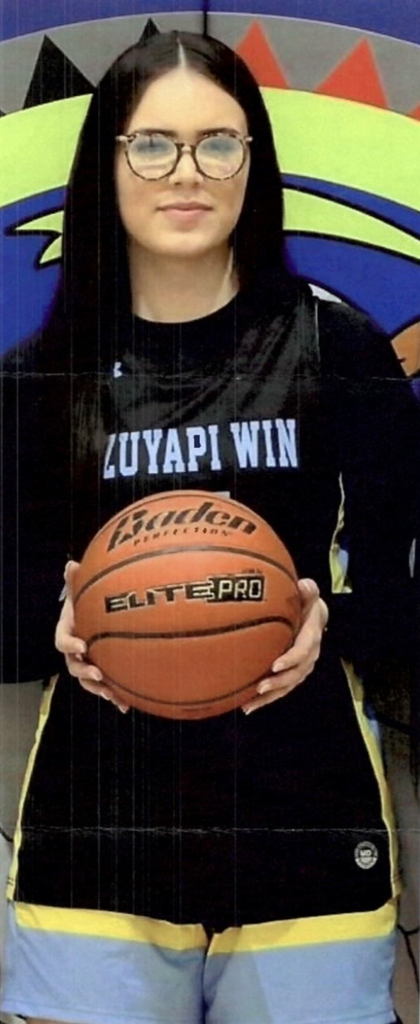 photo of a female Isanti basketball player in a black and blue uniform holding a basketball