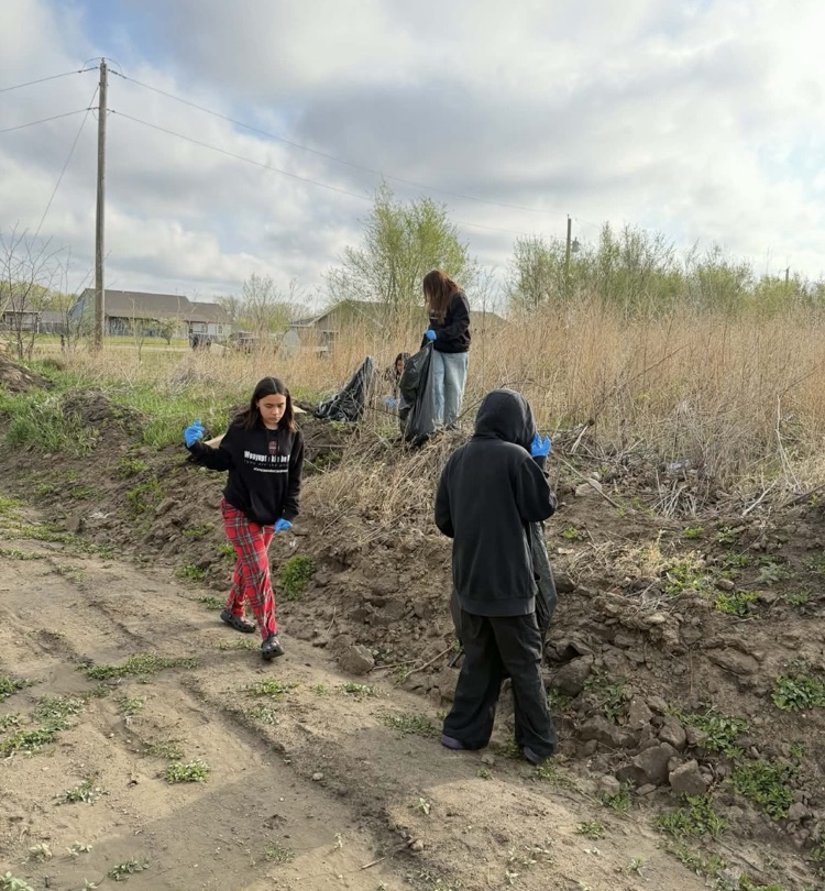 Photo of students picking up trash outside the school building