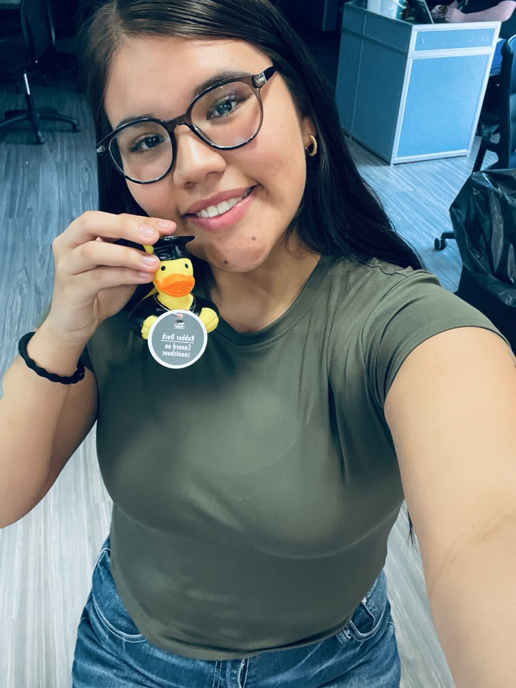Image of a female with glasses in a green shirt holding a rubber duck