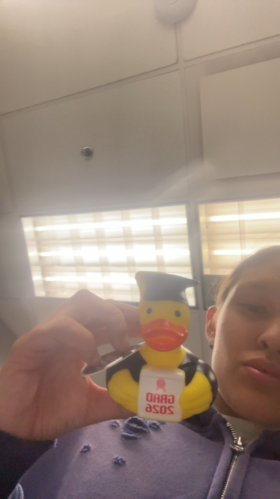 Image of a female and a purple sweater holding a rubber duck