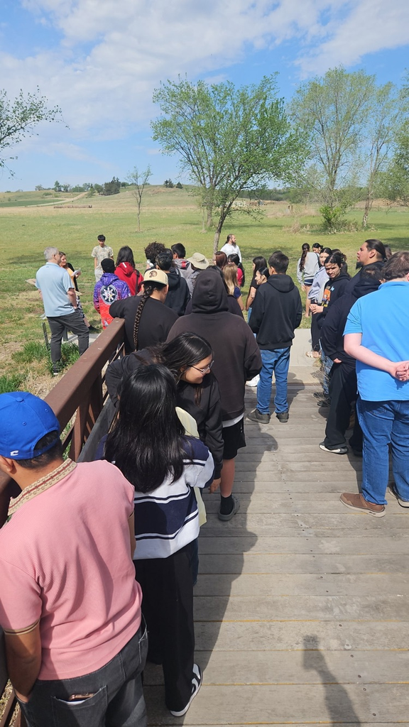 Students standing on a wooden bridge listening to a speaker