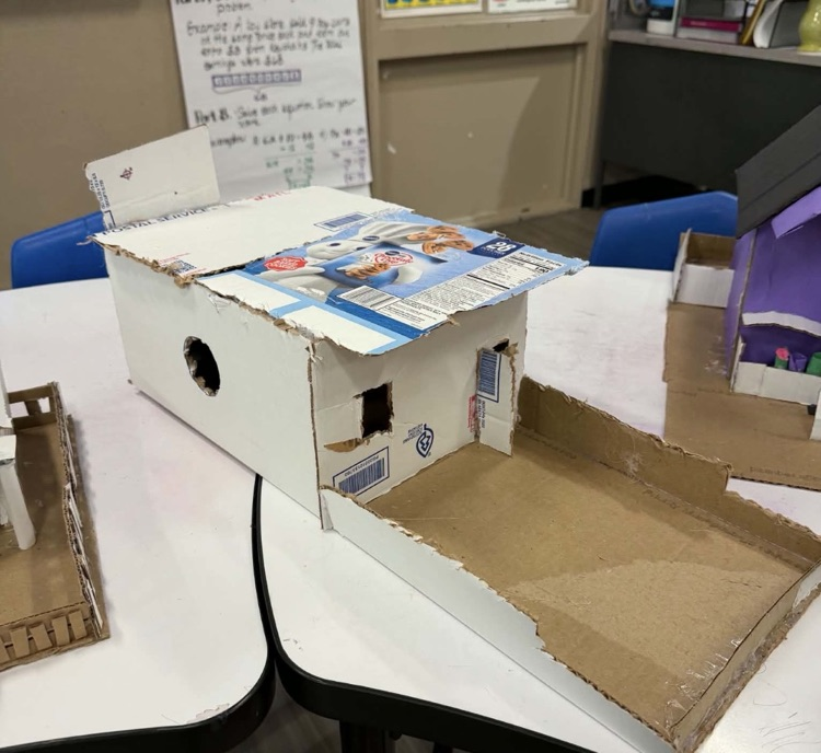 Photo of the middle school math project- building houses out of recycled materials. white and black house
