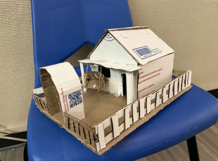 Photo of the middle school math project- building houses out of recycled materials. white and black house