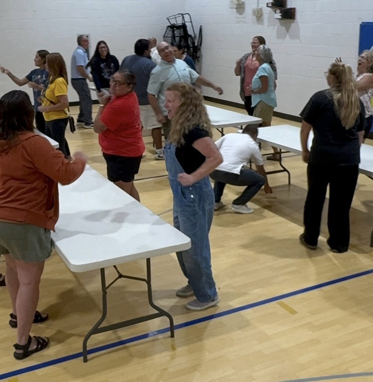 photo of school staff lined up by a table playing a game