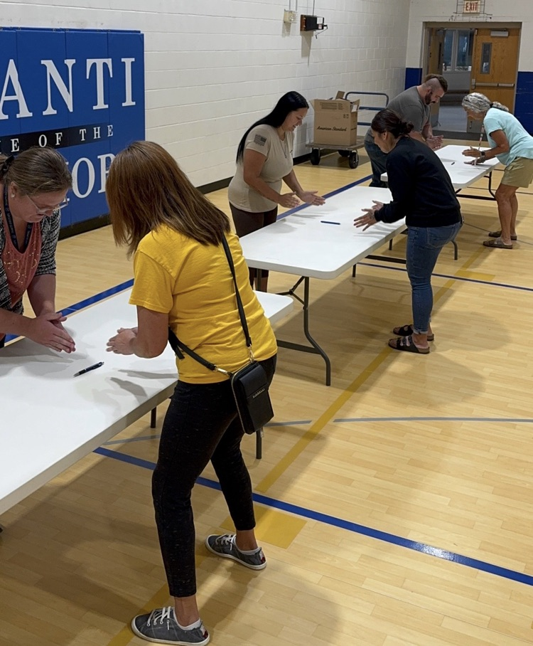 photo of school staff lined up by a table playing a game