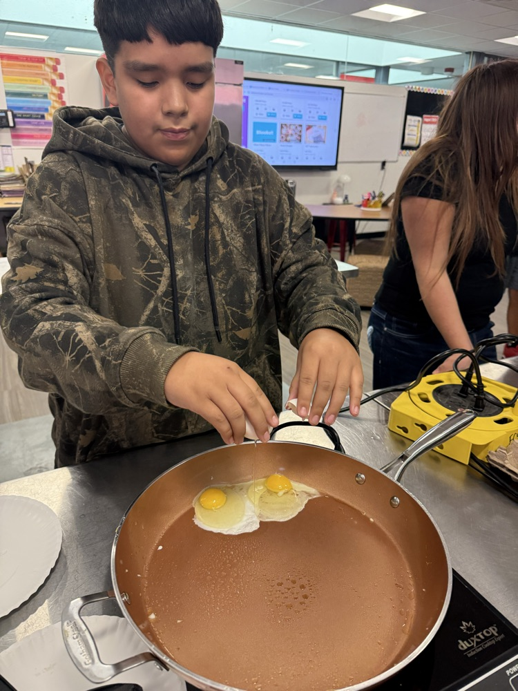Two students practice frying eggs during a Family and Consumer Sciences cooking lesson.