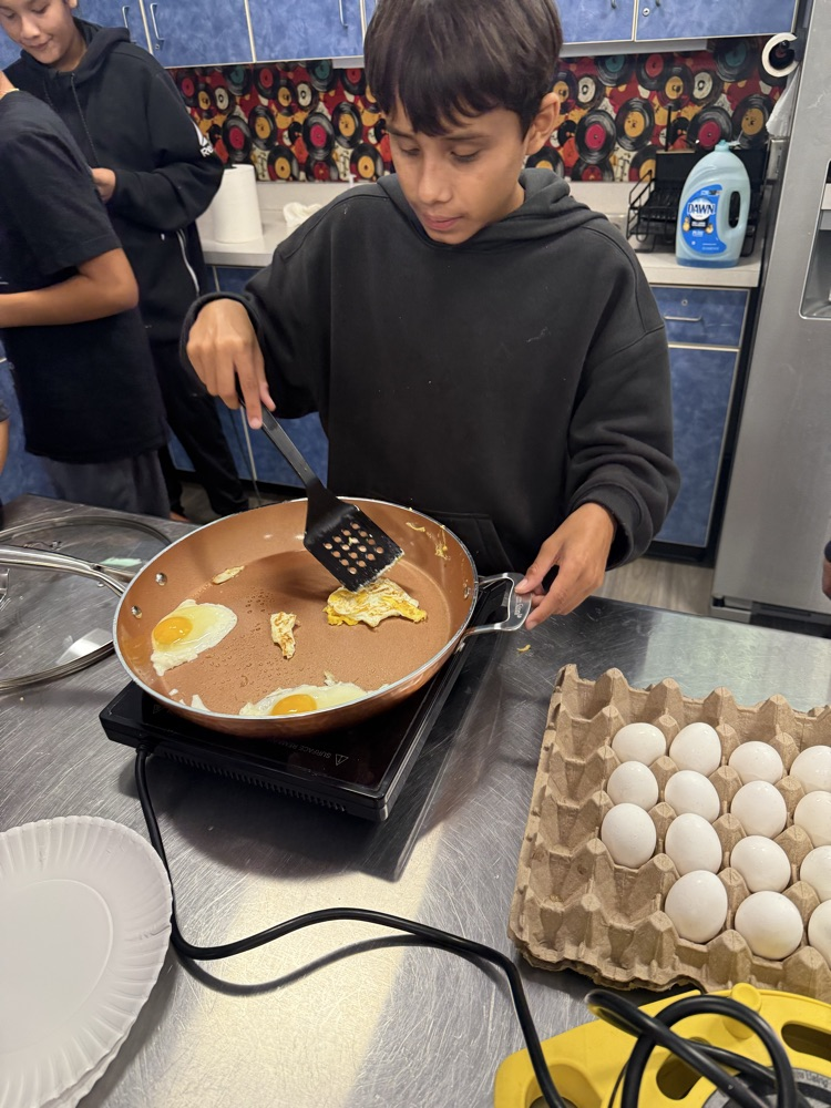 Two students practice frying eggs during a Family and Consumer Sciences cooking lesson.