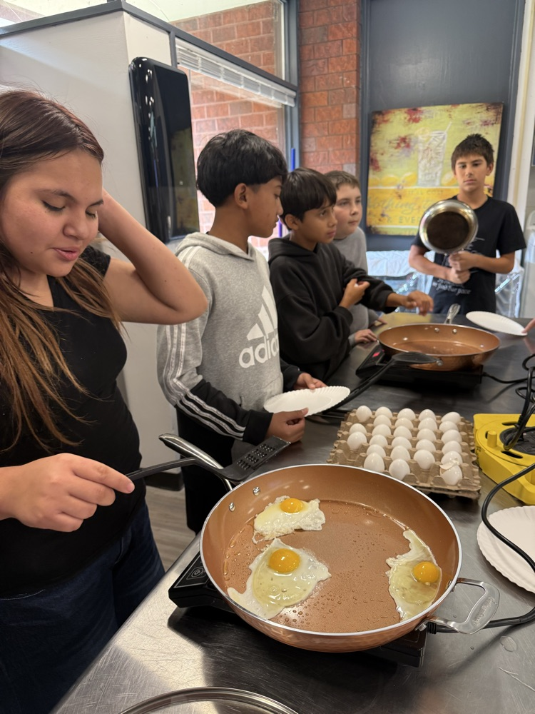 Two students practice frying eggs during a Family and Consumer Sciences cooking lesson.