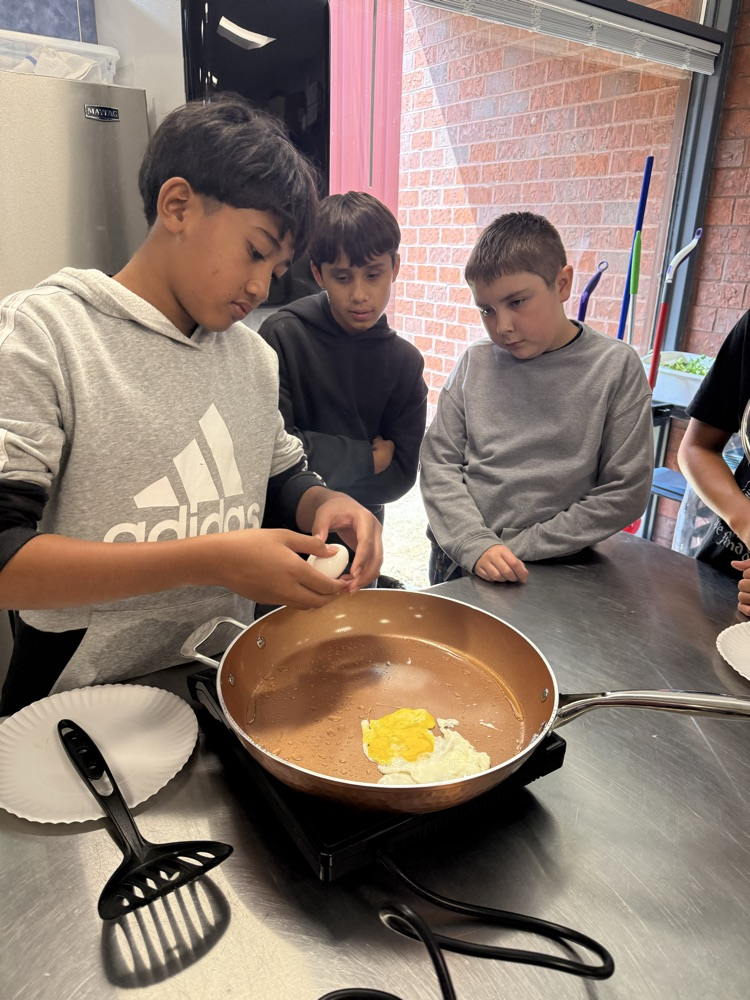 Students practice cracking and cooking eggs during a sixth grade Family and Consumer Sciences lesson.
