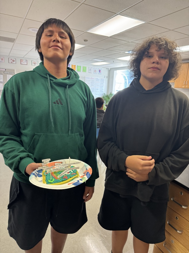 Photo of two male students holding a plate with the science project of a sale on it