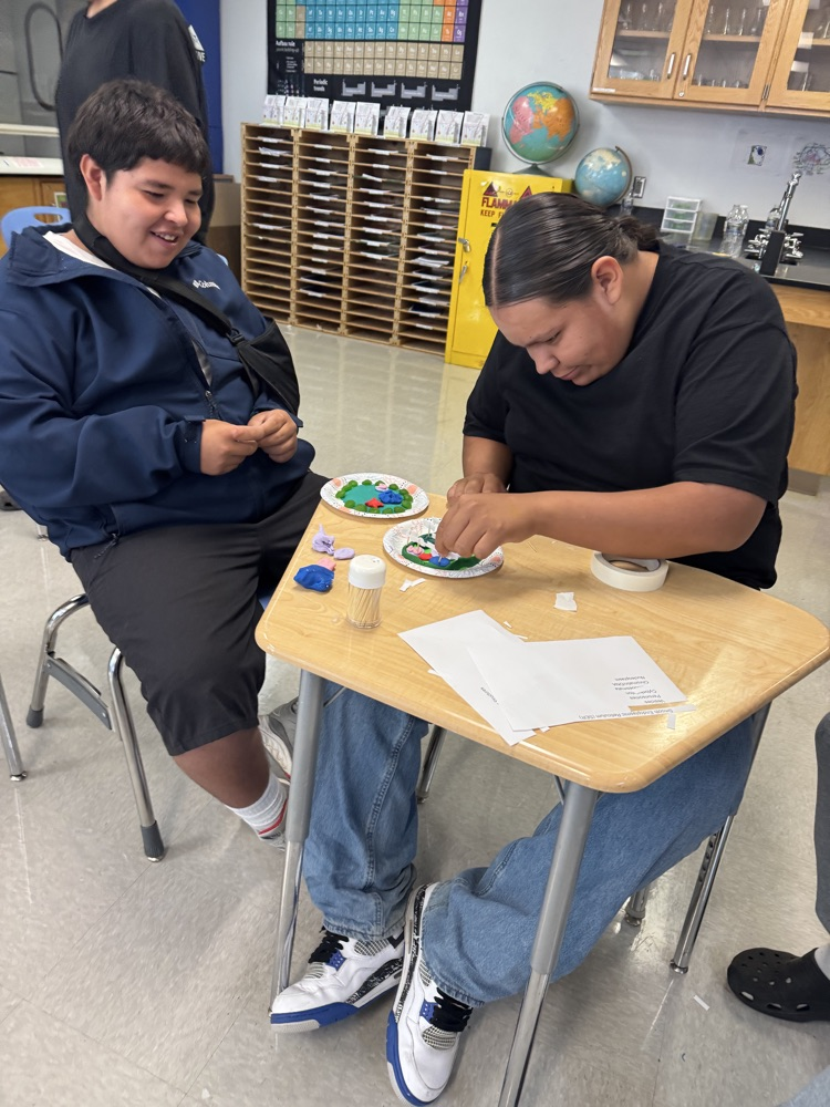 Photo of two male students creating a science project cell with play dough