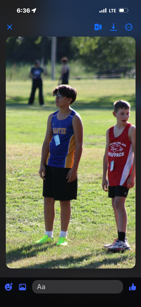 photo of student in a blue running uniform running on grass in a cross country meet 